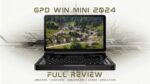 GPD WIN Mini 2024: Compacte handheld gaming-pc in open clamshell-positie. 7-inch scherm met hoge resolutie met een levendige luchtfoto van een landelijk dorp met traditionele huizen en weelderig groen. Volledig QWERTY-toetsenbord zichtbaar onder het scherm, wat wijst op dubbele functionaliteit voor gaming en productiviteit. Apparaat omringd door gestileerde printplaatpatronen die de technologische kracht benadrukken. Bovenaan staat de tekst “GPD WIN MINI 2024” en onderaan “FULL REVIEW”, met als subtekst “UNBOXING - OVERVIEW - BENCHMARKS - GAMES - EMULATORS”. De afbeelding combineert echte hardwarepresentatie met grafische elementen en suggereert een uitgebreide beoordeling van de mogelijkheden van het apparaat in verschillende gebruikssituaties. De zwarte behuizing contrasteert met de kleurrijke scherminhoud en benadrukt het slanke ontwerp en de draagbaarheid van het apparaat, terwijl het krachtige prestaties voor gaming en nog veel meer belooft.