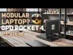 Immagine che mostra un laptop modulare, il GPD Pocket 4, su una moderna scrivania in legno in uno spazio di lavoro in stile industriale. La sovrapposizione di testo recita 'Laptop modulare? Recensione GPD Pocket 4' con un'emoji espressiva che mostra sorpresa, evidenziando il design modulare unico del dispositivo.