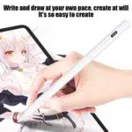 A hand uses a white stylus pen to draw or write on a tablet screen displaying an anime-style image. The text reads, "Write and draw at your own pace, create at will."