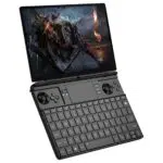 A black GPD WIN MAX 2 handheld gaming PC is shown open at an angle, displaying a vibrant fantasy action game on its screen with two armored characters. The device features a full QWERTY keyboard, an integrated touchpad, and game controllers with analog sticks, a D-pad, and action buttons.