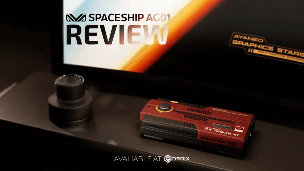 Slika recenzije proizvoda prikazuje tamnocrveni pravokutni uređaj, možda grafičku karticu ili mini PC, na kojem su vidljivi "RX 7600M XT" i "AYANEO GRAPHICS STARS". U pozadini se na zaslonu prikazuje "SPACESHIP AG01 REVIEW" s logotipom, a ispod uređaja tekst glasi "DOSTUPNO U DROIXU". Mali, tamni, cilindrični objekt nalazi se lijevo od uređaja.