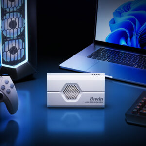 A lifestyle shot of the white SSD reader placed centrally on a blue-lit desk setup, flanked by a gaming PC tower, a game controller, and a laptop.