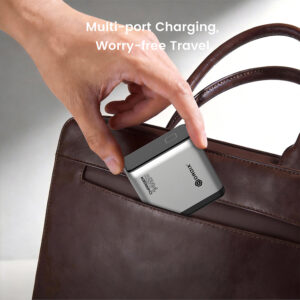 Hand placing a compact multi-port charger into a brown leather bag, promoting travel-friendly charging.