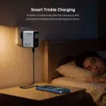 Väggmonterad smart laddare bredvid en säng, med en telefon som laddas på nattduksbordet.